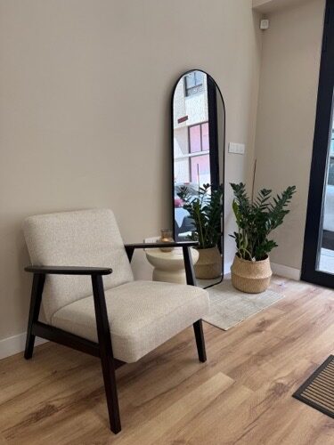 Lounge corner with linen armchair, arched mirror and plants